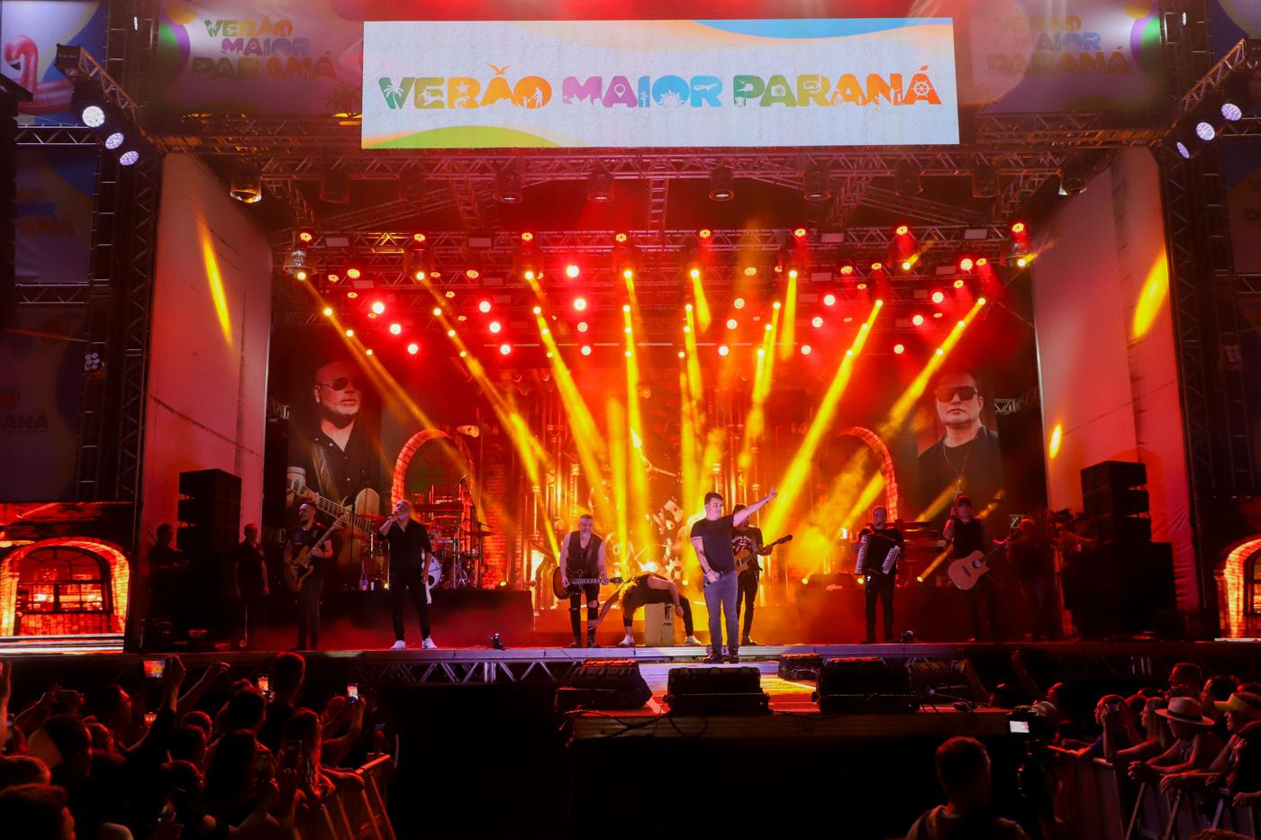 Palco de um show com feixes de luz e a banda