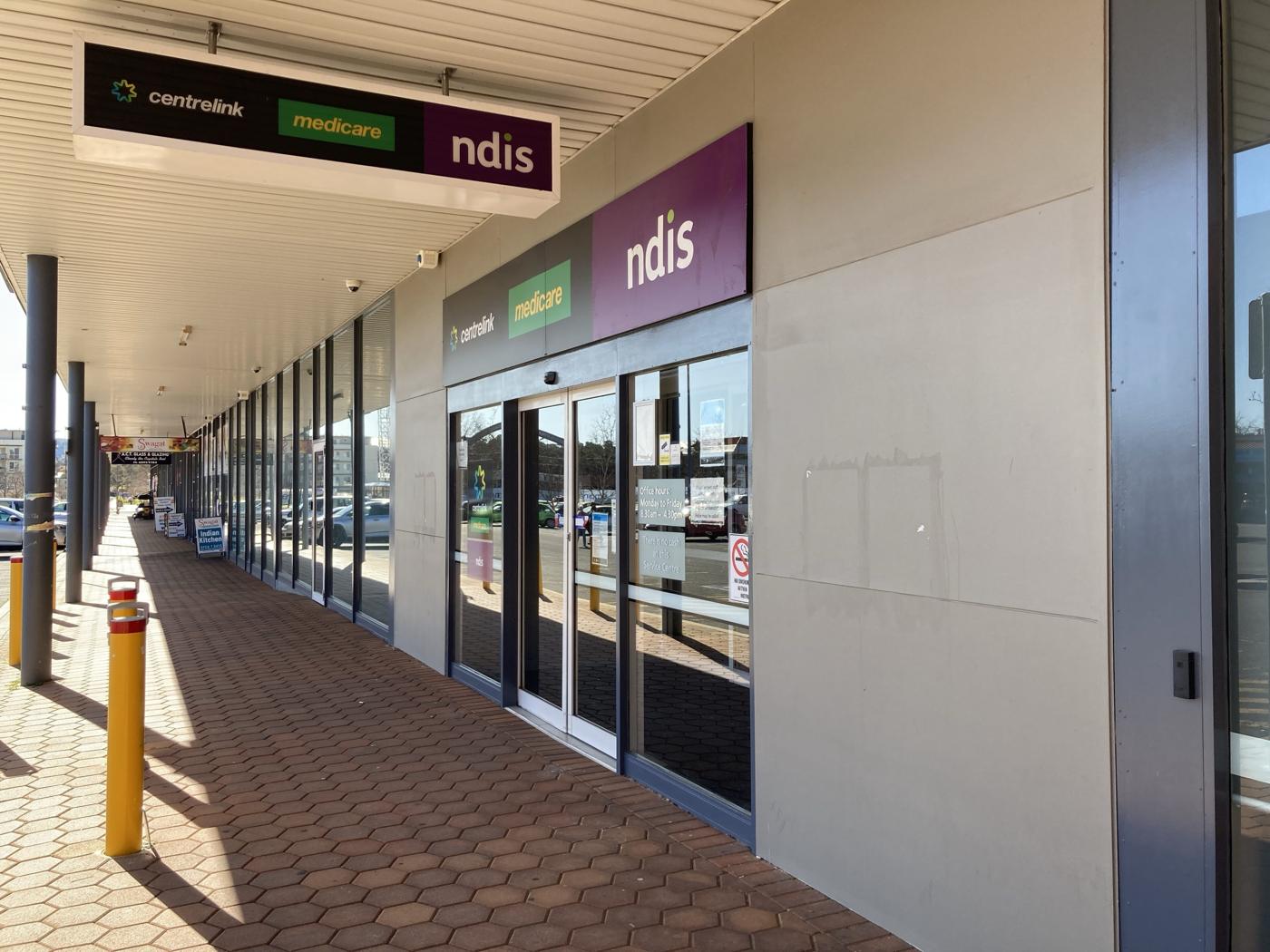 Entrada de um centro da Services Australia, com placas de Centrelink, Medicare e NDIS