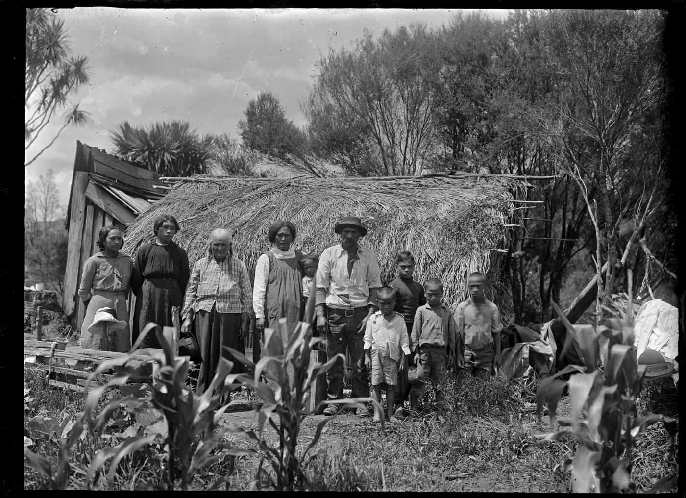 Família maori diante de uma casa de palha em 1918